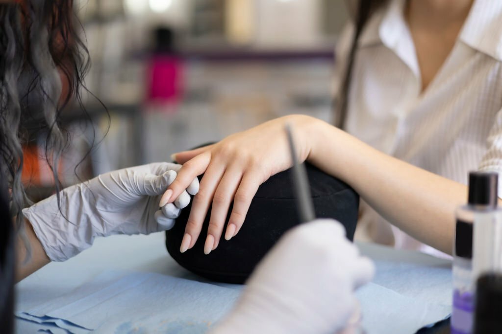 Manicurist applying acrylic on nails